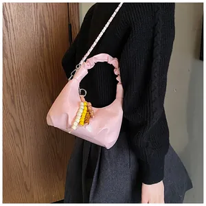 Detail of pink dumpling bag with pleated handle, chain strap and beaded tassel charm