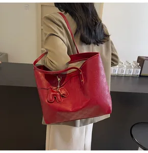 Detail of red tote bag featuring embossed grid texture and cute animal charm accessory