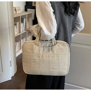 Detailed view of beige quilted laptop sleeve with square texture and top handle