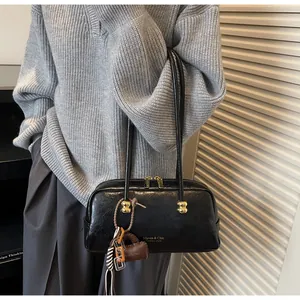 Detalle del bolso Boston vintage negro con textura de cuero encerado y herrajes dorados