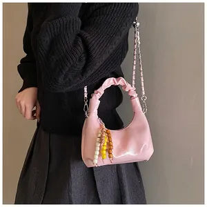 Pink pleated leather dumpling bag with beaded charm and gold chain strap detail