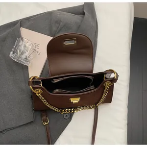 Detail of dark brown faux suede baguette bag with gold chain and multi-layer interior
