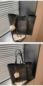Detail of grey washed denim tote bag with leather straps and plush sheep charm