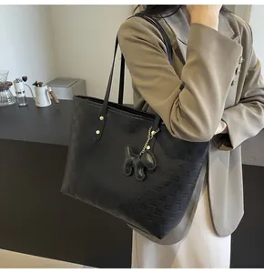 Detail of black checkered tote bag with puppy charm and elegant embossed leather texture