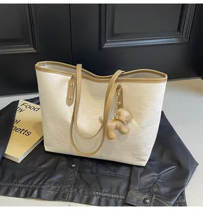 Detail of checkered embossed cream tote bag with puppy charm on black leather background