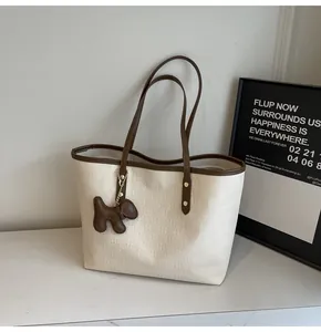 Detail of cream tote bag with checkered embossing and dark brown puppy charm