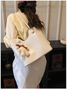 Detail of cream large tote bag with glossy finish and cute plush bear charm decoration