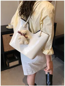 Chic off-white large tote bag with plush bear pendant shown on model's shoulder
