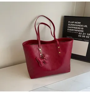 Close-up of red embossed leather tote bag featuring a cute dog-shaped charm pendant