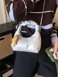 Chic cream dumpling bag with pleated handle and colorful wood beads crossbody strap