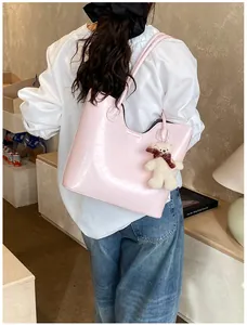 Close-up of pink glossy tote bag with U-shaped cutout and cute plush bear charm