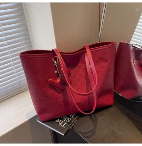 Detail of red leather tote bag with grid texture and cute dog charm in natural light