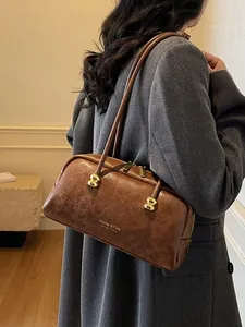 Bolso Boston vintage marrón con asas largas y logo Maven & Chic mostrado en modelo
