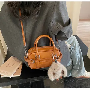 Sac baguette en cuir marron avec breloque lapin porté en bandoulière sur une tenue