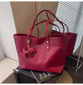 Detail view of burgundy tote bag with embossed checkerboard pattern and puppy charm