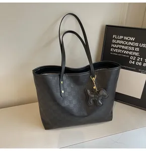 Detail of black tote bag with checkered embossing and cute leather puppy charm accessory