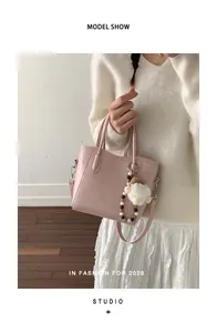 Détail du sac à main en cuir rose avec breloque ours en peluche et porte-clés perlé