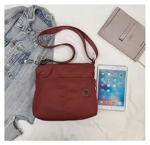 Deep red nylon tote bag shown with an iPad and book to demonstrate its large capacity