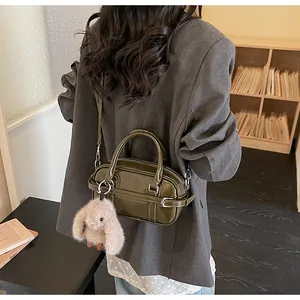 Détail d'un sac à main en cuir verni vert olive avec un joli pendentif lapin en peluche