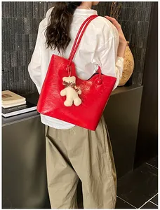 Chic large red glossy tote bag with white plush bear charm shown in daily wear context
