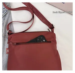 Detail of burgundy nylon tote bag showing the functional back zipper pocket for smartphones