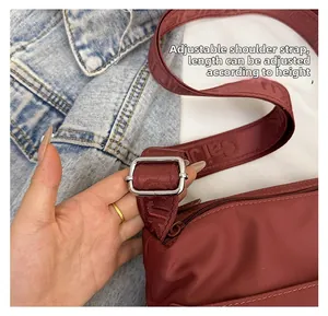 Detail view of the burgundy nylon tote bag with an adjustable branded silver buckle strap
