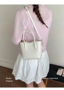 Mini sac cabas crème chic porté avec un haut en tricot rose et une jupe blanche stylée