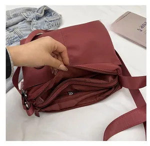 Macro view of burgundy nylon tote interior showing multiple zipper compartments and large capacity