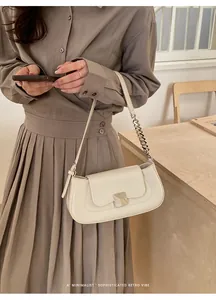 Detail of cream white baguette bag with square metal buckle and silver chain strap detail