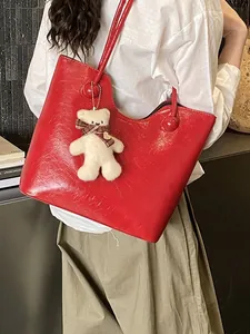 Large red faux leather tote bag with glossy finish and cute teddy bear charm