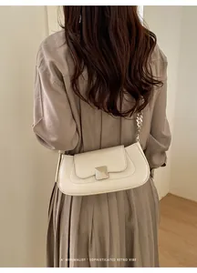 Minimalist beige baguette bag with silver chain strap shown in a chic indoor setting