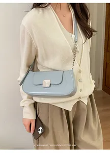 Detail showing the square brushed metal clasp and leather strap of the light blue baguette bag