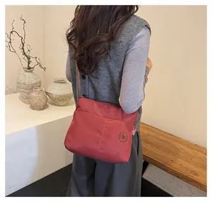 Detail of red nylon tote bag with multi-pocket design and adjustable strap for daily use