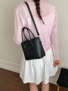 Sac seau noir classique avec double poignée et bandoulière fine porté par un modèle