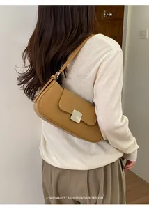 Minimalist khaki baguette bag with silver buckle worn by a model in a retro vibe scene