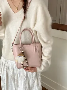 Sac seau en cuir PU rose avec breloque peluche et bandoulière montrée sur mannequin femme