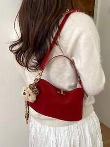 Borsa baguette in pelle rosso scuro con ciondolo a forma di orso indossata da modella