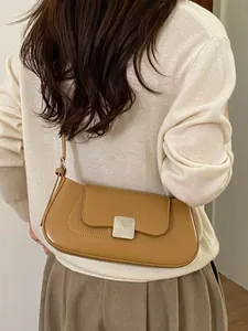 Minimalist light brown leather baguette bag worn by a model in a stylish street setting