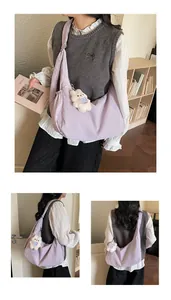 Detail view of light purple crescent shoulder bag with white teddy bear charm and soft folds