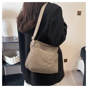 Detail view of khaki nylon crossbody bag with embossed strap and logo on model
