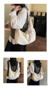 Detail of off-white canvas hobo bag with zip closure and plush rabbit charm