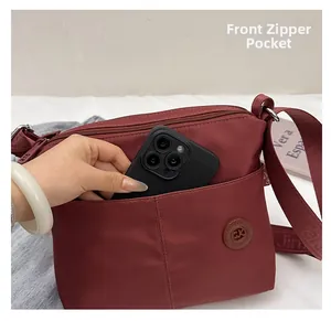 Detailed view of the front zipper pocket on a maroon nylon tote showing phone storage