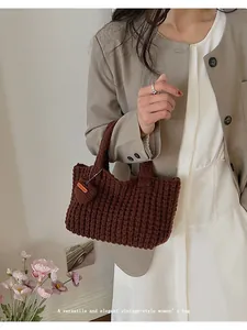 Detalle del bolso de punto marrón hecho a mano con etiqueta de cuero y textura vertical