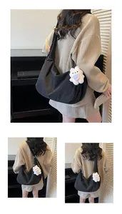 Detail of black nylon crescent tote bag with a cute white bunny plush pendant