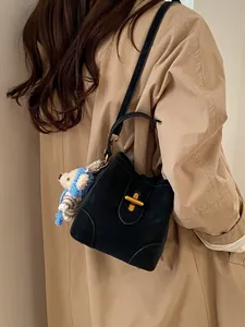 Schwarze Eimer-Handtasche aus Leder mit goldenem Schloss und Bärenanhänger für Damen