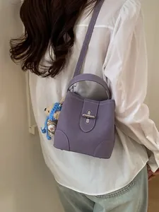 Lilane Beuteltasche mit weißen Nähten und Bärenanhänger an einem Casual-Model