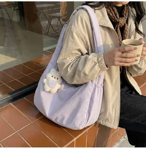 Detail of light purple nylon half-moon crossbody bag with cute white bear plush charm
