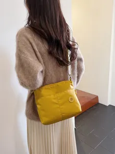 Bright yellow nylon crossbody tote bag with zipper pockets and adjustable strap shown on model