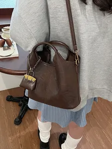 Classic dark brown leather bucket bag with top handle and crossbody strap for women