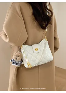 White quilted crossbody bag with golden clasp and cute puppy charm on a wool coat